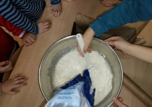 Dziecko wsypuje mąkę do miski.